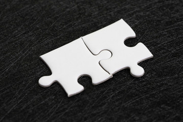 Closed up of white jigsaw puzzle on dark black background using as answer, solution, completion or strategy for business success