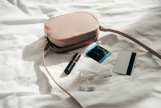 pink bag near lipstick, earphones, credit card and comdom