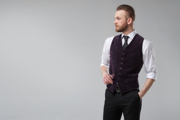 Elegant man in a vest and tie on a gray background.