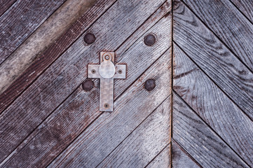 Close up of an old church door with keyhole in the shape of a cross. Texture of an old ancient  wooden door.