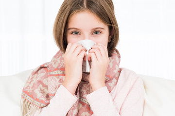 Little ill girl holding napkin to sneeze