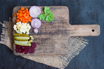 Boiled cut vegetables, carrots, beets, potatoes, pickled cucumber on wooden rustic background, healthy food concept