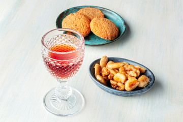 A photo of a glass of sweet wine with cookies and nuts, with a place for text
