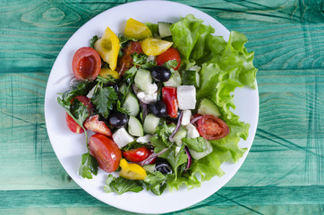 Vegetable salad cucumber capsicum tomato and olives on a white plate natural background with copy space