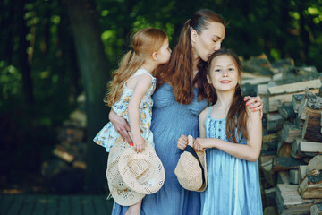 beautiful long-haired mother in a long blue dress in sunny summer forest walks with his beautiful...