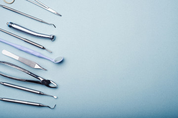 Dental steel instruments on light blue background with copy space