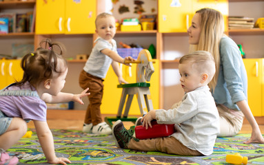 Nursery babies with mentor playing in kindergarten