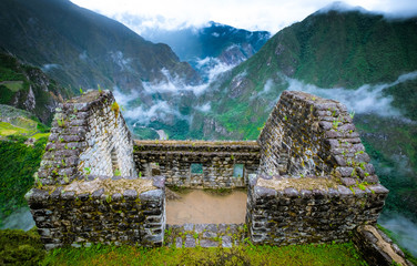 Sunshine breathtaking view of Machupicchu stone anchient walls and temple among mountains covered with clouds