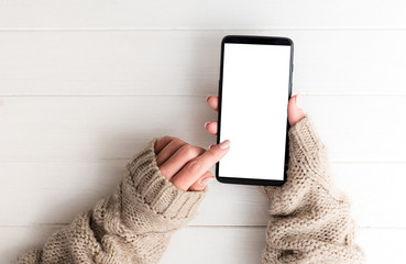 Top view of girl in sweater using smartphone on white table background