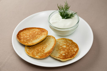 pancakes with sour cream in a white plate
