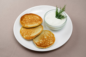 Fototapeta na wymiar pancakes with sour cream in a white plate