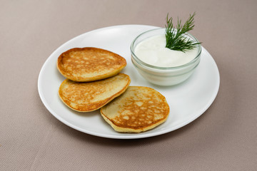 pancakes with sour cream in a white plate