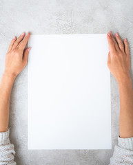 Girl's hands holding a big white sheet of paper