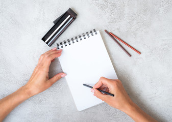 Girl's hands drawing in notebook on a table