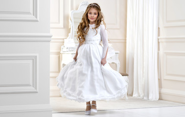 Portrait of cute little girl on white dress and wreath on first holy communion background church...