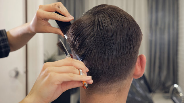 back view of female barber haircut doing male hair style.