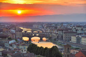 Fototapeta na wymiar View of the River Arno and famous bridge Ponte Vecchio. Amazing evening golden hour light. Beautiful gold sunset in Florence, Italy