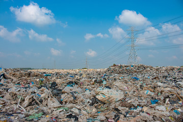 big garbage mountain with blue sky and high voltage pole background