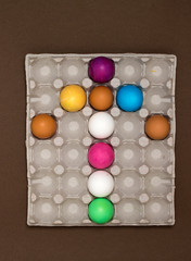 Beautiful creative arrow made of colored eggs in a tray on brown background. Pointer or cursor from eggs. 
