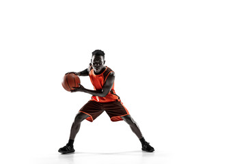 Naklejka na ściany i meble Full length portrait of a basketball player with a ball isolated on white studio background. advertising concept. Fit african anerican athlete with ball. Motion, activity, movement concepts.