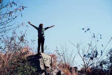 African Man traveler with film camera  standing on top of a mountain and looking at fly seagull
