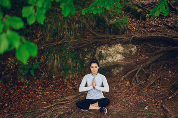 beautiful girl in a tracksuit sitting in green forest 