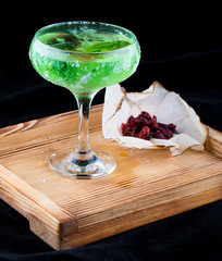 Cocktail Chartreuse on a wooden Board with candied fruit. On dark background