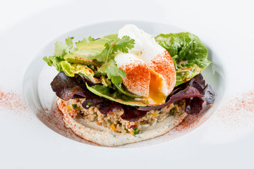 Poached egg with quinoa and salad on a white plate