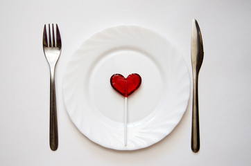 heart on a white plate with fork and knife