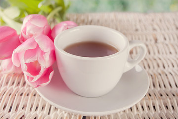 A cup of tea and pink tulips on the table