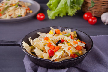 Farfalle italian pasta with mix vegetables on a iron black pan