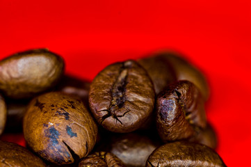 Brown roasted coffee beans on red background, close up, macro