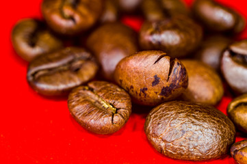 Brown roasted coffee beans on red background, close up, macro