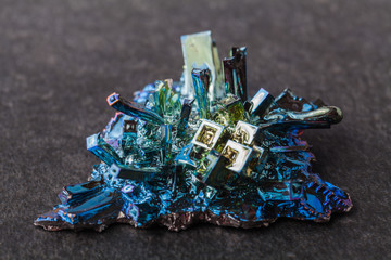 Crystal of bismuth on dark stone background