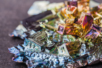 bismuth (rainbow metal) on the dark stone background