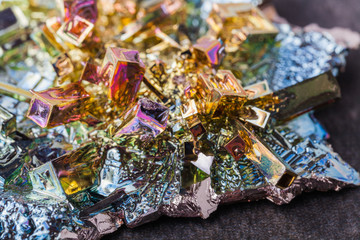 Crystal of bismuth on dark stone background