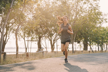 Fototapeta premium young woman runner running on running road in city park