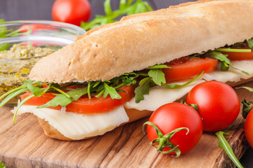 Toasted panini with ham, cheese and arugula sandwich on cutting board