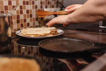 Traditional russian blin (pancake) on a cast-iron frying pan. Dough, cooking blinov. Pancake week. Celebration of Maslenitsa