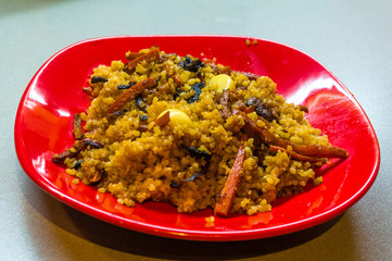 Uzbek pilaf with meat in a red plate on a wooden table, close up