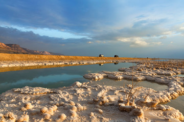 Crystal formations of mineral salts in the waters of the Dead Sea. Coastline with mountains on the...