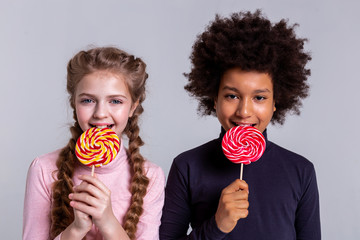 Smiling dark-haired boy with black eyes eating candy