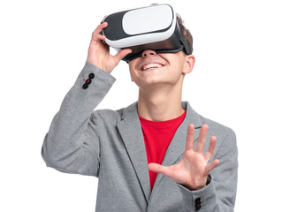 Happy Teen Boy wearing Virtual Reality Goggles watching movies or playing video games, isolated on white. Cheerful Teenager looking in VR glasses. Funny Child experiencing 3D gadget technology.