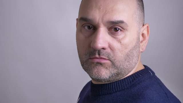 Closeup shoot of middle-aged caucasian man turning to the camera and looking forward with emotionless facial expression