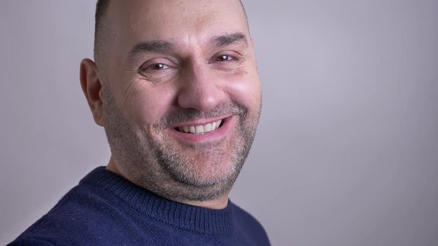 Closeup shoot of middle-aged caucasian man turning to the camera and looking forward while smiling happily