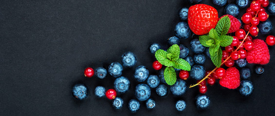 Berry mix on a black background with copy space. Strawberry, Raspberry, Red currant, Blueberry and Blackberry, top view