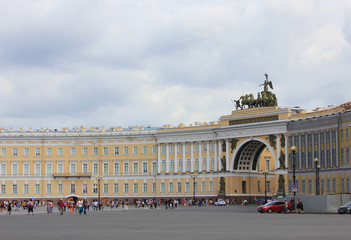 Obraz premium Palace square and arch of General Staff building in St. Petersburg, Russia. Scenic cityscape with tourists visiting on summer cloudy day and empty copy space for text