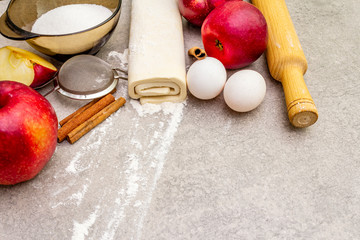 Apple pie ingredients baking concept. Fresh apples with cinnamon, flour, sugar, eggs. Cooking process on stone background, top view
