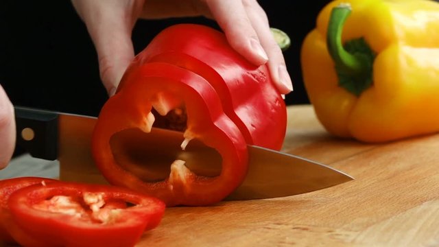 Slow motion knife cuts the red pepper. A sweet pepper is cut on a cutting board. Bulgarian pepper.