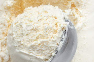 Scooped Vanilla ice cream with a scoop in frozen  container. White ice-cream,  top view.